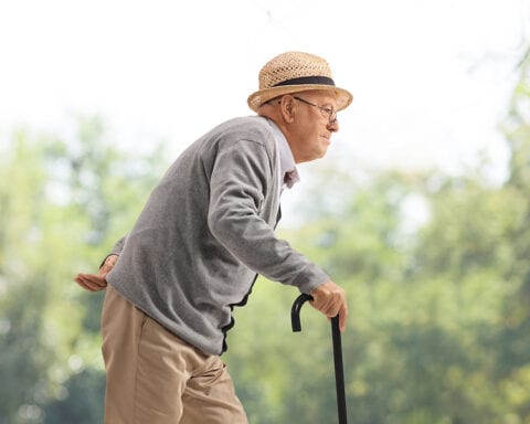 Elderly man walking with a cane in a park