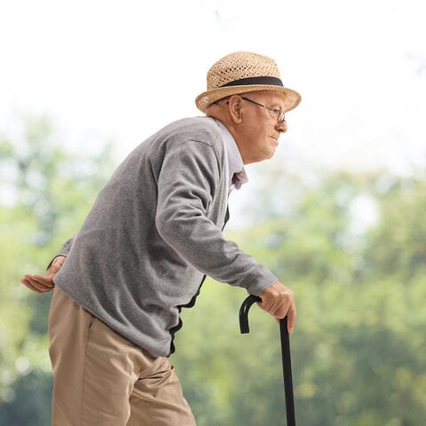 Elderly man walking with a cane in a park