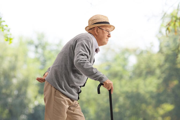 Elderly man walking with a cane in a park