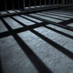 Bars from a prison jail cast a shadow on the floro.