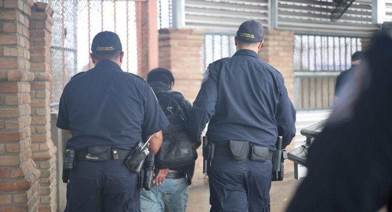 CBP officers escort a wanted person at a U.S. port of entry