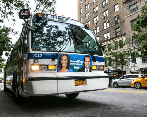 An MTA bus stands idle with lights flashing in the street in Manhattan.