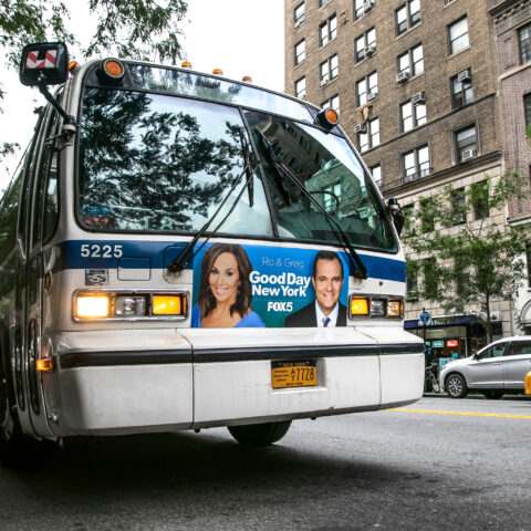 An mta bus stands idle with lights flashing in the street in manhattan.