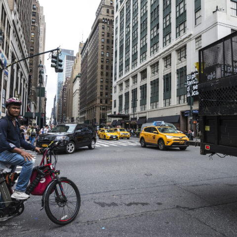 New york city, usa - july 25, 2018: seventh avenue and 34th street with a cyclist with an electric bike and people around in manhattan in new york city,