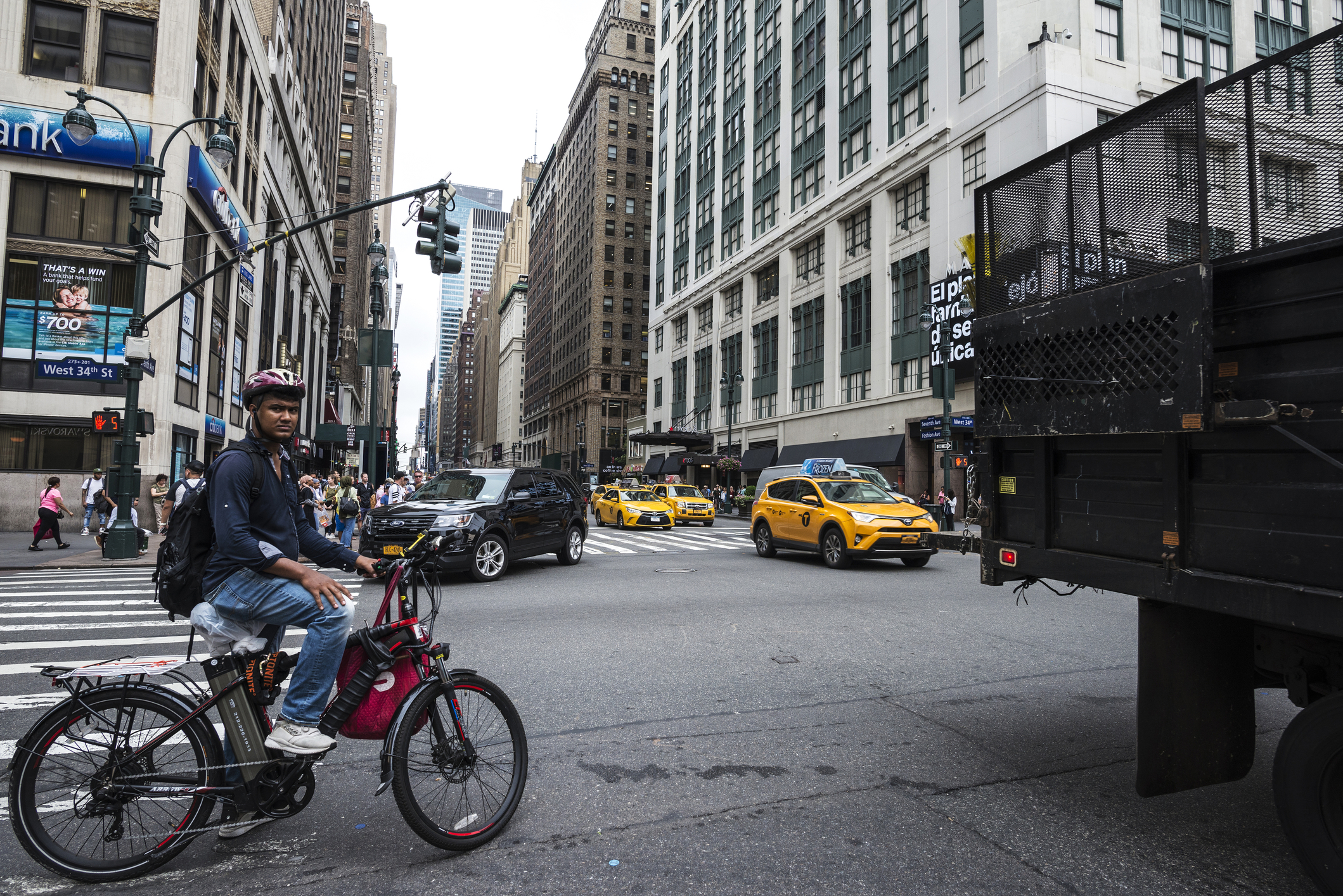 New York City, USA - July 25, 2018: Seventh Avenue and 34th Street with a cyclist with an electric bike and people around in Manhattan in New York City,