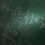 Math problem writing on a chalk board