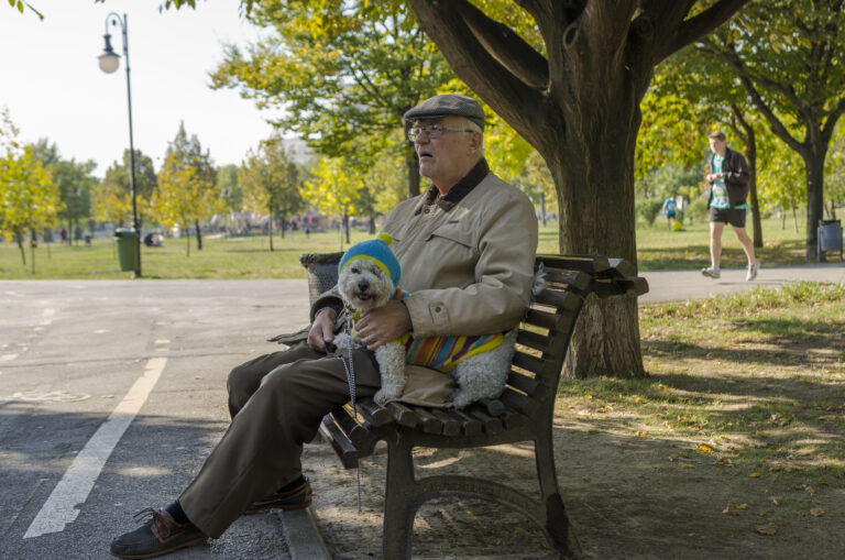 Old man and a little cute dog sitting and resting on bench on october 05,