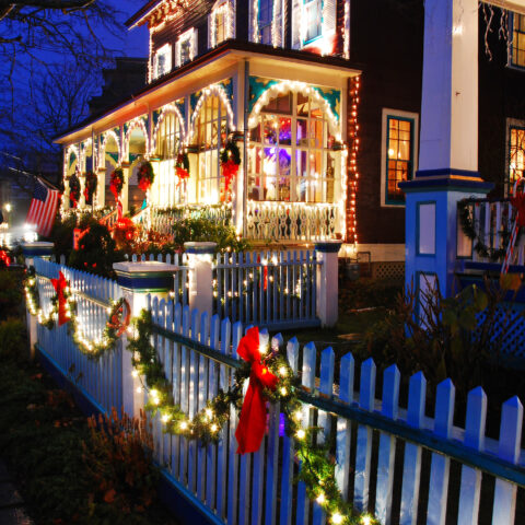 Christmas lights adorn a white picket fence bordering a stately victorian home in cape may, new jersey - photo by james kirkikis