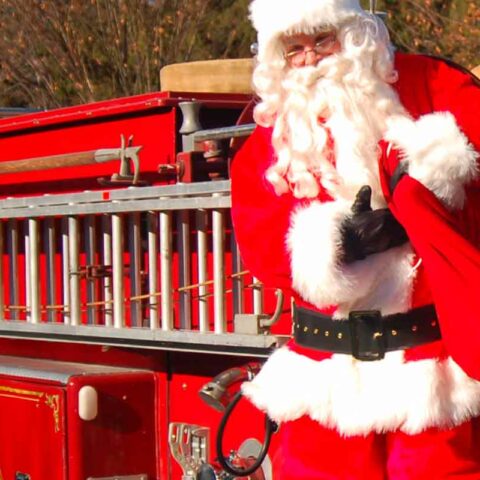 Santa claus arriving on fire truck.