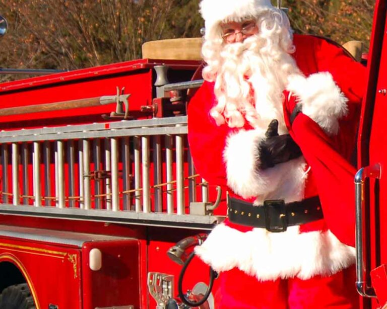 Santa claus arriving on fire truck.