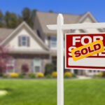 Sold Home For Sale Real Estate Sign in Front of Beautiful New House.