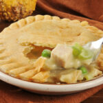 A forkful of turkey pot pie on a Thanksgiving type dinner table setting