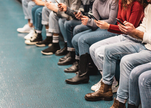 A-group-of-people-sit-while-checking-their-smart-phones