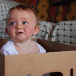 A baby inside a cardboard box.
