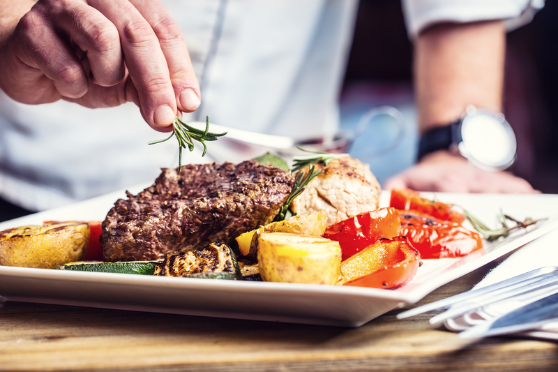 Chef in hotel or restaurant kitchen cooking only hands. Prepared beef steak with vegetable decoration