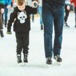 Child and father skating at ice rink.