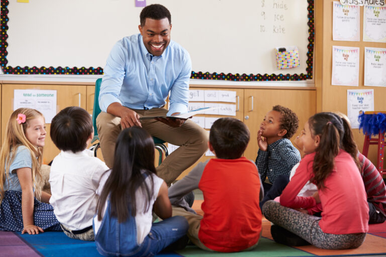 Elementary-school-kids-sitting-around-teacher-in-a-classroom