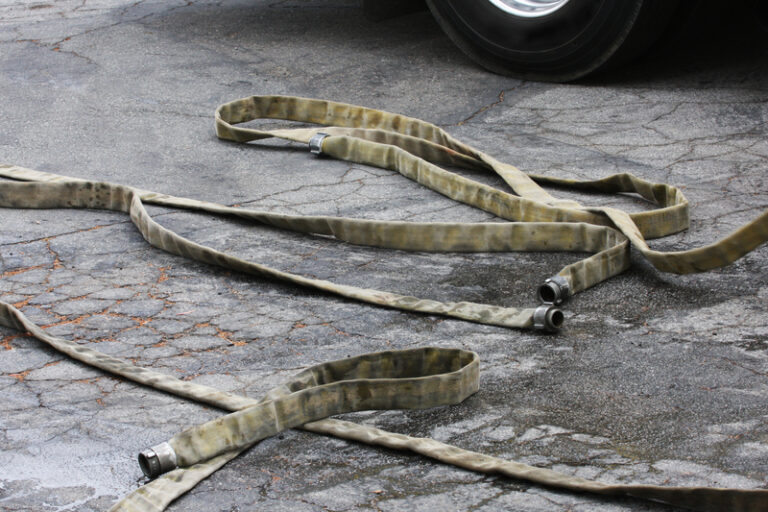 Fire hoses next to a fire engine, waiting to be stored back on the truck.
