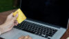 Plastic-credit-card-in-hand-and-use-of-laptop-for-internet-purchase