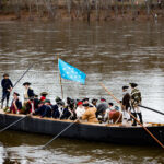 Reenactors portray General Washington and the Continental Army crossing the Delaware River in boats on Christmas Day.