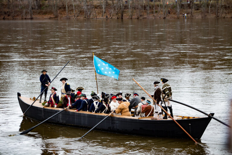 Reenactors portray General Washington and the Continental Army crossing the Delaware River in boats on Christmas Day.