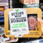 Shoppers hand holding a package of Beyond Meat brand plant based burger patties
