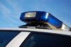 The blue lights of a police car, set upon a blue sky background.