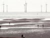 Wind turbines off the shore of a beach