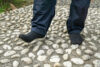 Man wearing socks on cobblestone sidewalk
