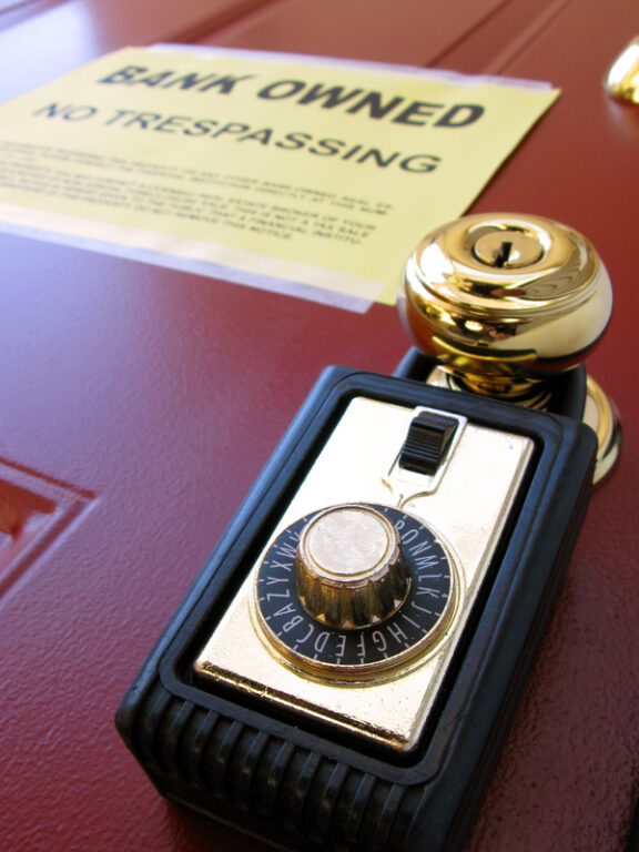 Real estate Realtor combination lock box on foreclosed house door with attached lender bank owned no trespassing foreclosure notice of repossession