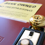 Real estate Realtor combination lock box on foreclosed house door with attached lender bank owned no trespassing foreclosure notice of repossession