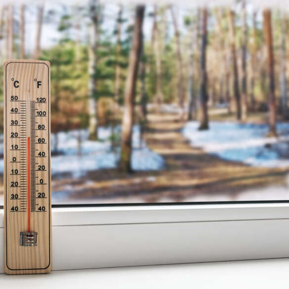 Thermometer on a frozen window and cold weather in the spring street.