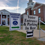 polling location at a school in Rutherford, New Jersey. In the background, a voter can be seen about to enter through the double doors.