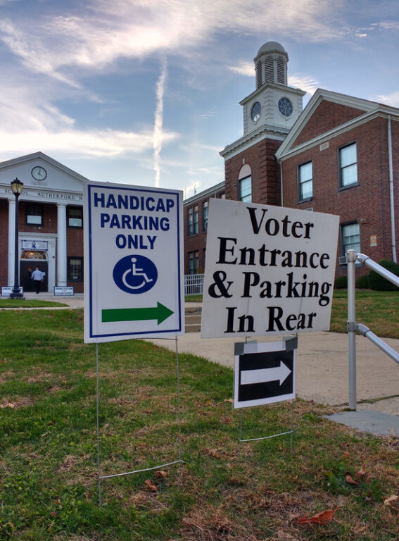 polling location at a school in Rutherford, New Jersey. In the background, a voter can be seen about to enter through the double doors.