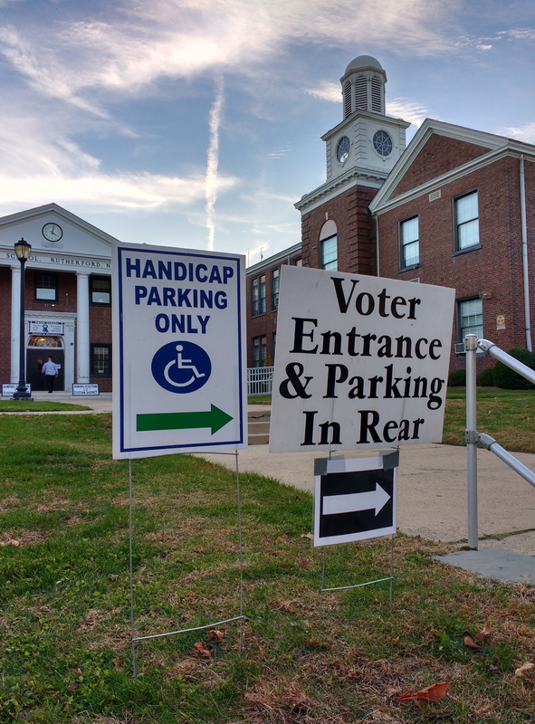 polling location at a school in Rutherford, New Jersey. In the background, a voter can be seen about to enter through the double doors.