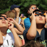 Looking Up At The Solar Eclipse. A group of children looking up at the 2017 solar eclipse, using protective glasses at the Livingston Library terrace in Livingston,NJ.