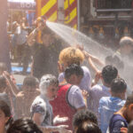 Kids cooling off on a hot day with help of firefighters - File Photo