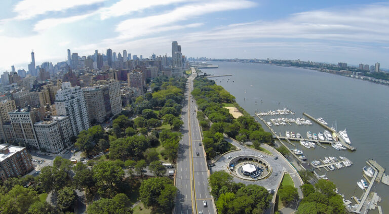 Cars ride by henry hudson parkway near riverside park and 79th street boat basin at summer sunny day. Aerial view