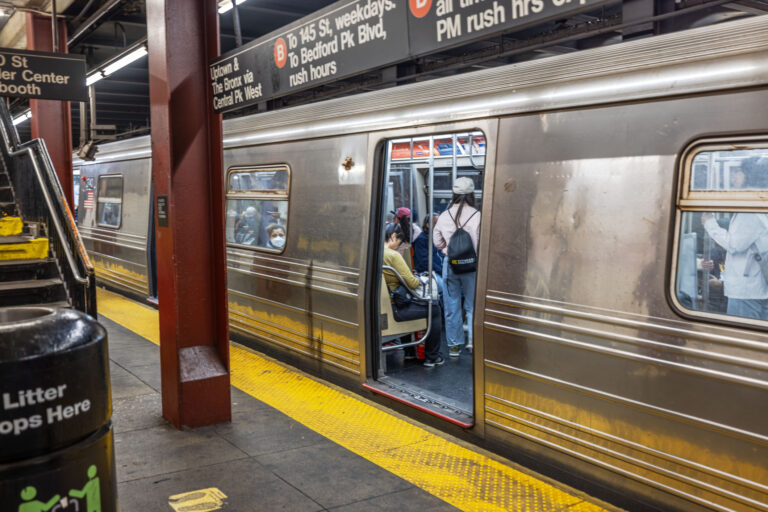 New york city subway station with passengers entering train, platform safety line and urban transit signage. New york. Usa.
