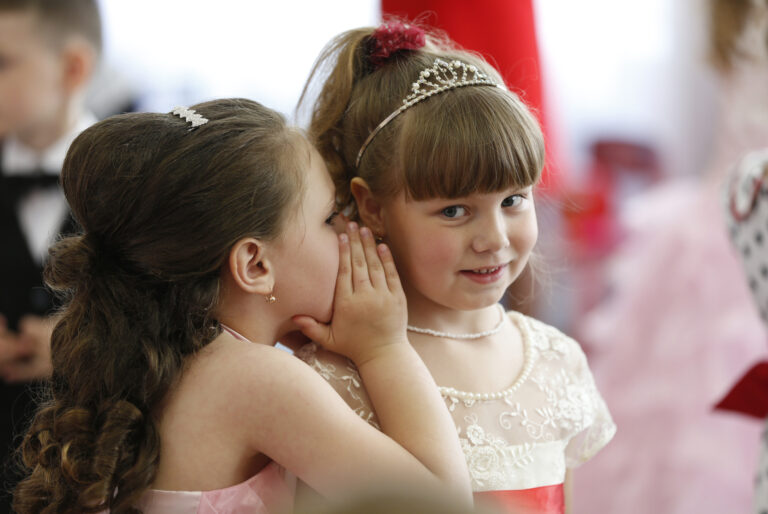 Girls whispering to each other.