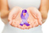 Hands holding purple awareness ribbon. Healthcare and social problems concept - womans hands holding purple domestic violence awareness ribbon.
