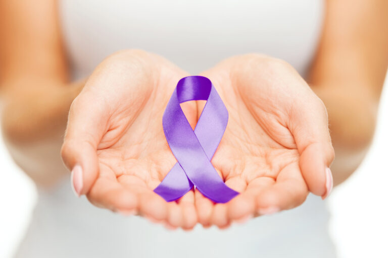 Hands holding purple awareness ribbon. Healthcare and social problems concept - womans hands holding purple domestic violence awareness ribbon.