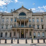 Exterior view of New Jersey State House building in Trenton, NJ. The New Jersey State House is located on the W. State Street in downtown Trenton. The Capitol is the most historic public building in New Jersey, comprised of the State Legislature, the Governor`s Office and other Executive branch offices.