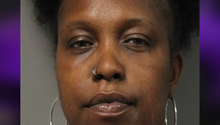Close-up portrait of a Black woman with a nose ring and large hoop earrings, neutral expression.