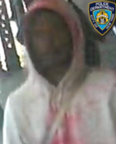 Surveillance image of a hooded person with face blurred, wearing a light-colored jacket and pink shirt, with a police badge overlay in the corner.