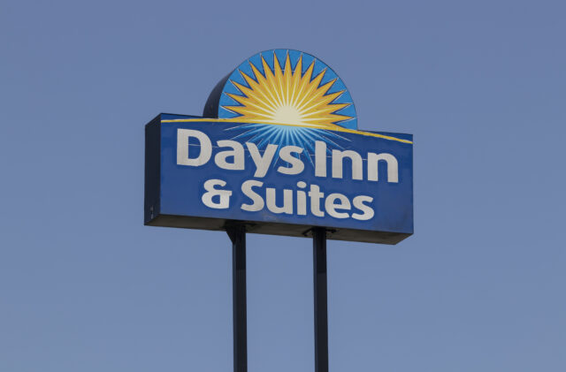 Days inn & suites sign featuring a blue panel with a yellow sunburst against a clear blue sky.