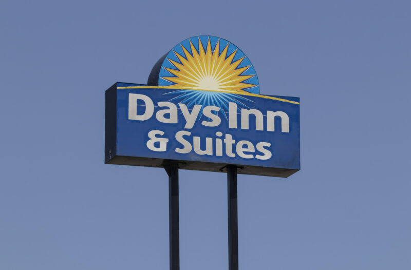 Days inn & suites sign featuring a blue panel with a yellow sunburst against a clear blue sky.