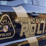 Maryland Natural Resources Police car door with badge emblem and bold POLICE lettering on a dark blue vehicle.