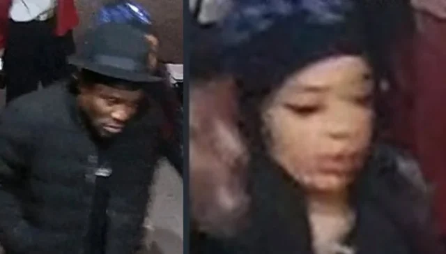 Surveillance-style image of two people: a man in a black coat and hat on the left, and a woman with dark hair and a head covering on the right in a dim setting.