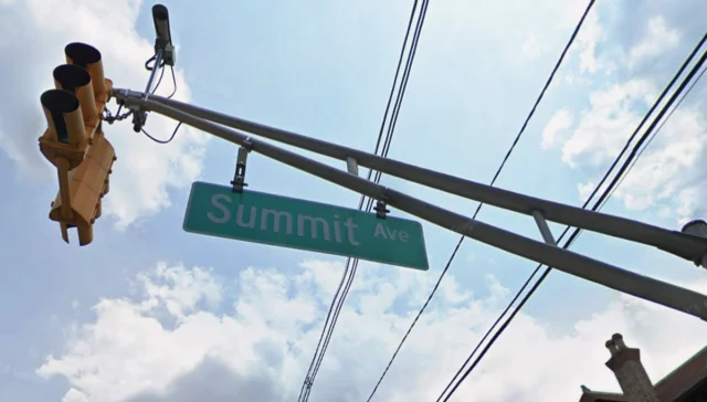Street sign reading 'summit ave' hanging from a utility pole against a blue sky with traffic lights and power lines overhead.